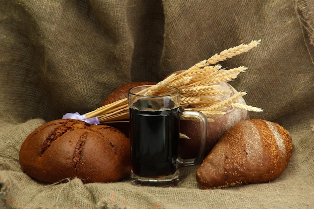 Caneca de kvass e pães de centeio com orelhas em fundo de serapilheira