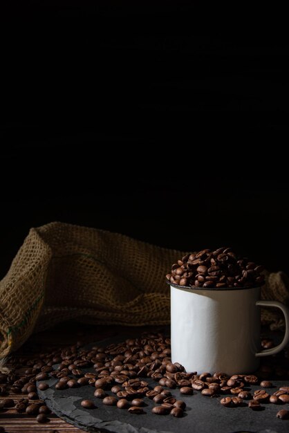 Caneca de louça de café e grãos de café em uma pedra cinza sobre foco seletivo de foto de estilo de comida escura de madeira