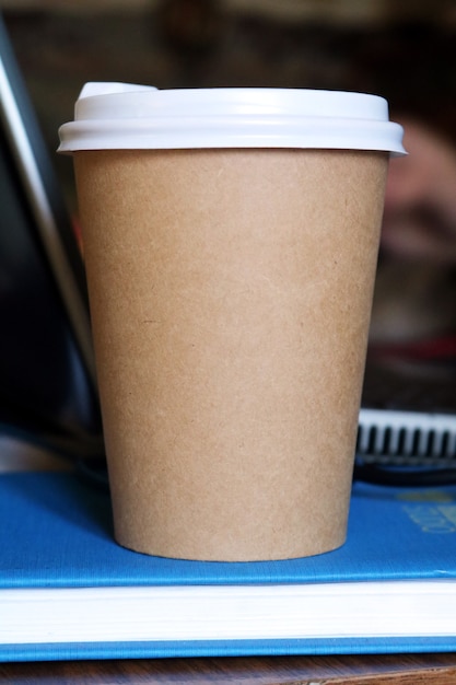 Caneca de papel para bebida em um caderno azul