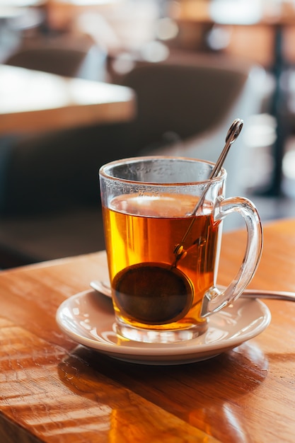 Caneca de vidro de chá quente em um café com fundo borrado. luz natural