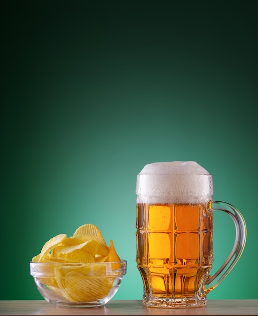 Caneca lapidada de cerveja light com espuma e batatas fritas