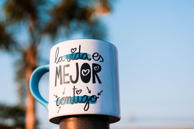 Foto caneca pequena com frase pensativa ao ar livre caneca no fundo da rua do céu azul