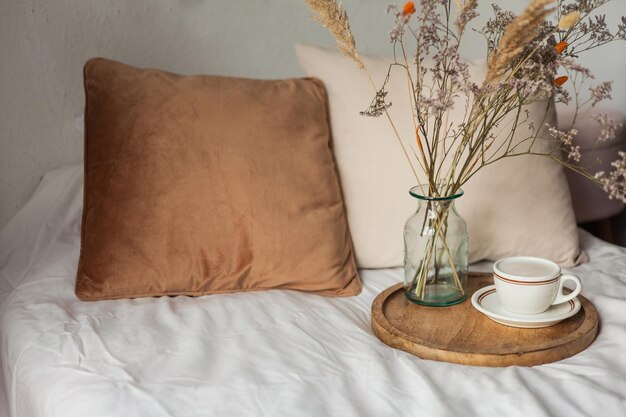 Caneca quente de cappuccino na bandeja de madeira na cama buquê de café da manhã de flores secas Cenário de primavera Casa aconchegante Cores naturais bege