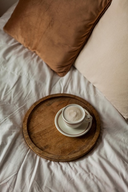 Caneca quente de cappuccino na bandeja de madeira na cama café da manhã Casa aconchegante Bege cores naturais Estética