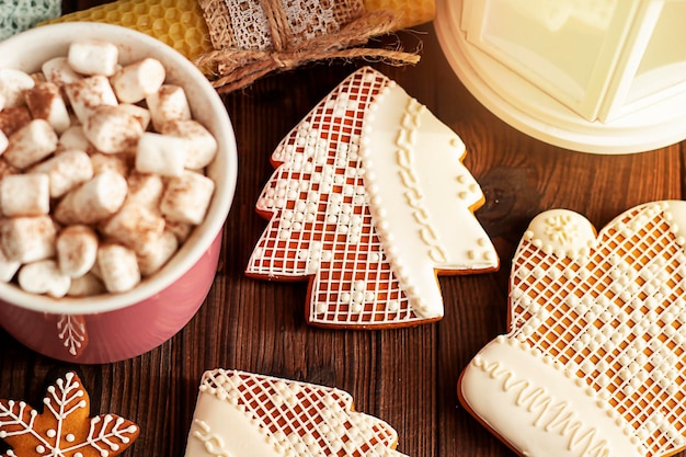 Caneca rosa com marshmallows de pão de gengibre coberto de neve ramos de pinheiro em um fundo de madeira com um ga