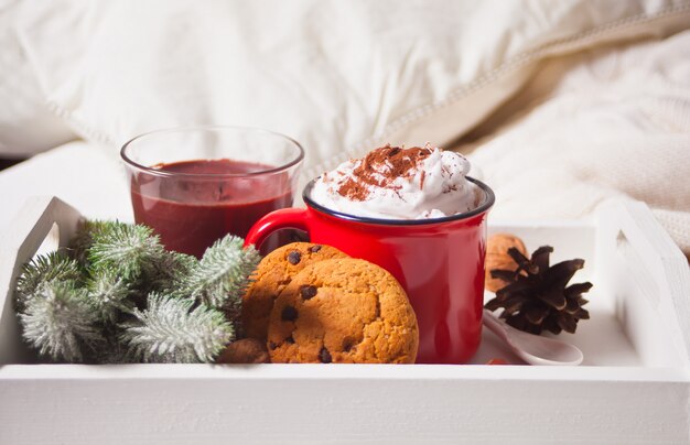 Caneca vermelha de cacau na bandeja branca na cama de manhã cedo de inverno