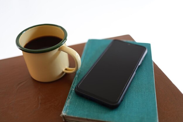 Canecas de café amarelas, telefones e livros na mesa de madeira dentro da casa.