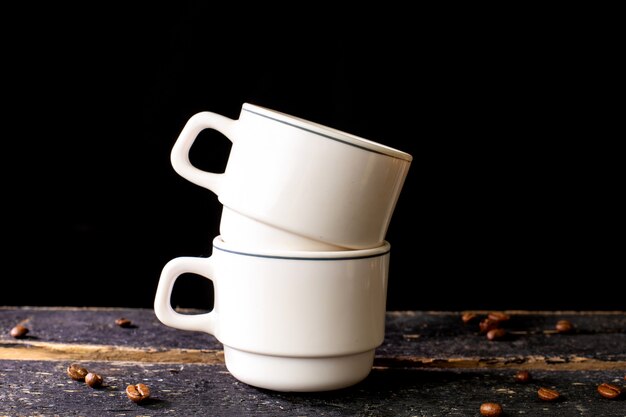 Foto canecas de café branco na tabela de madeira e no fundo preto com espaço para o texto.