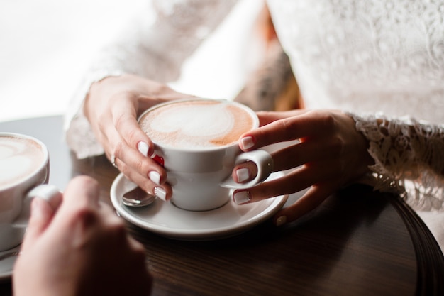 Canecas de café de cappuccino no casal de mãos