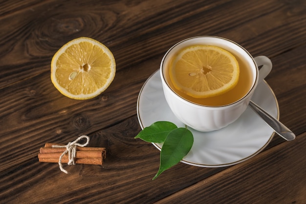 Canela, limão e uma xícara de chá em uma mesa de madeira. Uma bebida revigorante útil para a saúde.