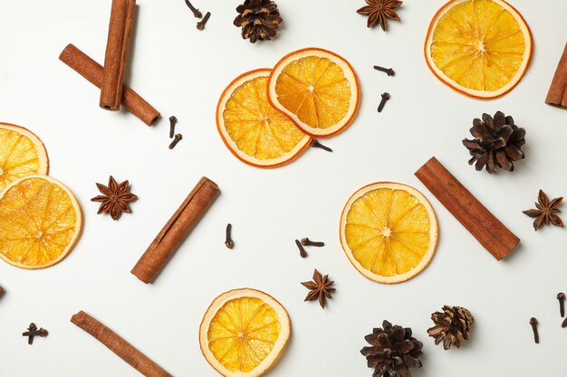 Canela, rodajas de naranja y conos sobre fondo blanco.