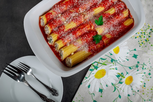 Canelones de pasta italiana con carne y salsa de tomate y queso en la mesa