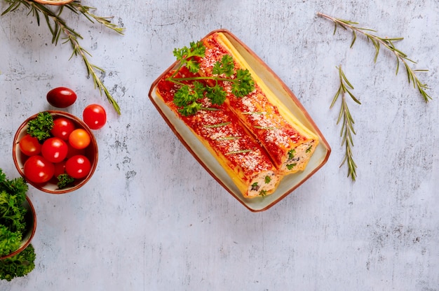 Canelones de pasta jumbo en plato con tomate