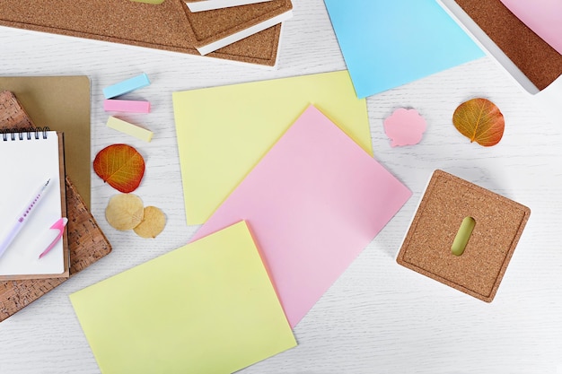 Foto caneta com papéis de adesivos de caderno e folhas secas na mesa branca