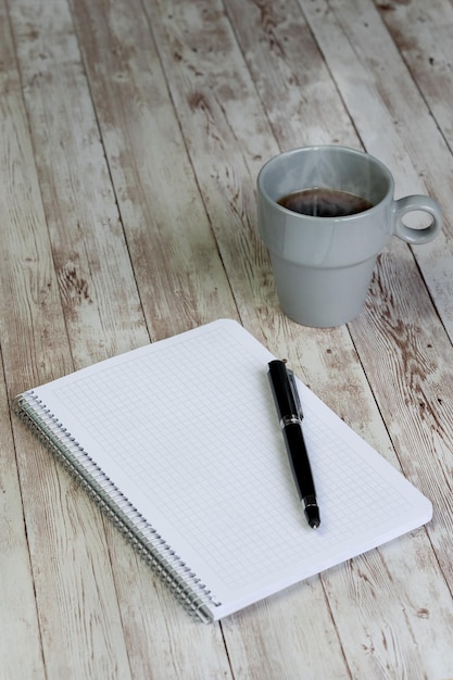 Caneta de café quente e objetivos de conceito de caderno em branco e plano de ação para o ano novo