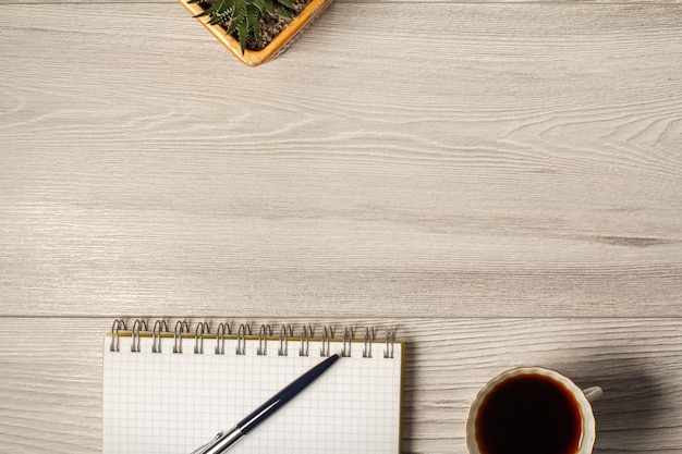 Caneta de notebook e xícara de café em um fundo cinza de madeira