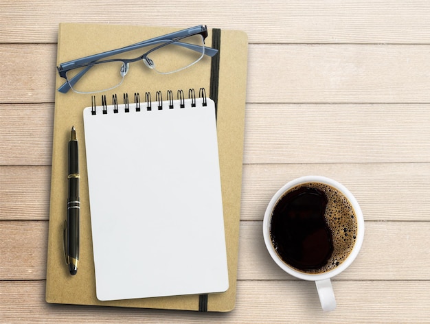 Caneta de óculos em branco e xícara de café no fundo da mesa de escritório