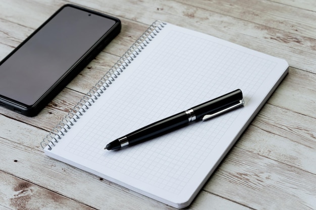 Caneta de smartphone e objetivos de conceito de caderno em branco e plano de ação de ano novo