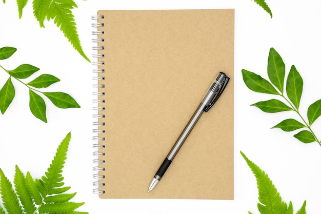 Caneta em caderno com folhas verdes