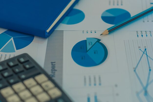 Caneta em gráfico de diagramas e relatórios de negócios de gráficos com dinheiro, bússola, calculadora na mesa de consultor financeiro. Conceito de Planejamento Contábil e Financeiro. vista do topo.