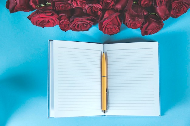 Foto caneta no bloco de notas com rosas vermelhas