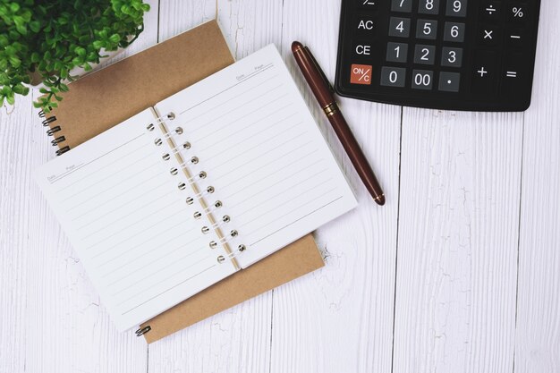 Caneta ou caneta de tinta com papel de caderno e calculadora na mesa de trabalho de madeira com espaço de cópia