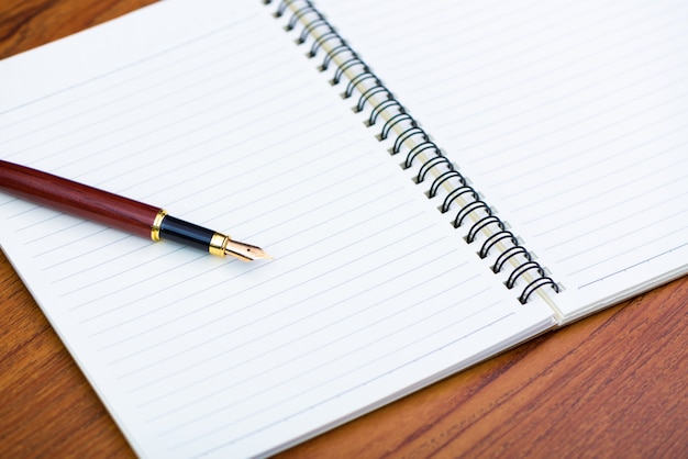 Caneta ou caneta de tinta com papel de caderno na mesa