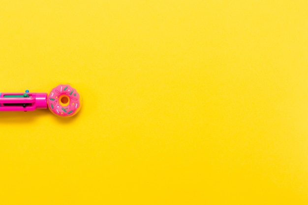 Caneta rosa na forma de um donut isolada em um fundo amarelo Caneta multicolorida Voltar às aulas