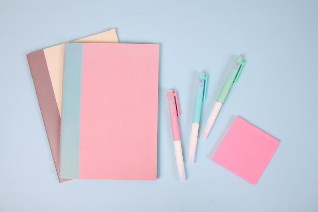 canetas de livros pastel e notas adesivas em fundo azul conceito de papelaria de volta à escola