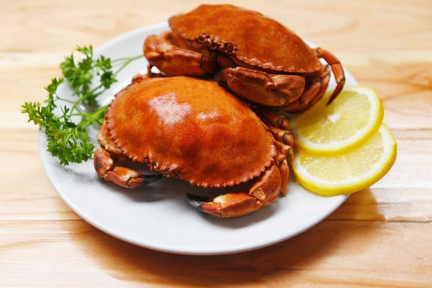 Cangrejo cocido en un plato con hierbas de limón y especias en la madera Ensalada de cangrejos de piedra roja hervida de mariscos