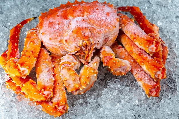 cangrejo rojo grande de Kamchatka, se encuentra sobre hielo, con garras, cereza, rodajas de limón y lima se cortan en rodajas redondas