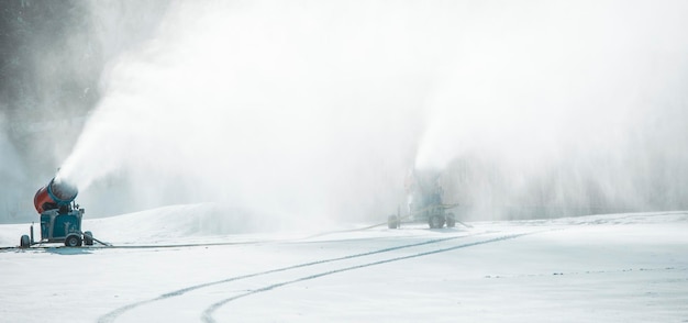 Canhão de neve nas montanhas de inverno. Pistola de neve que pulveriza cristais de gelo artificiais. Máquina fazendo neve.