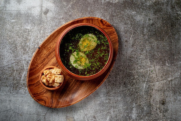 Canja de galinha com ovo cozido polvilhada com endro e salsa em uma tigela de madeira com migalhas de pão carrinhos isolados sobre uma mesa de pedra, Flatlay