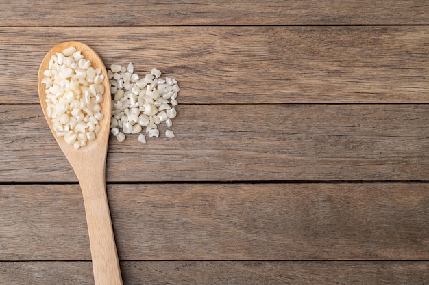 Canjica hominy o maíz blanco seco en una cuchara sobre una mesa de madera con espacio para copiar