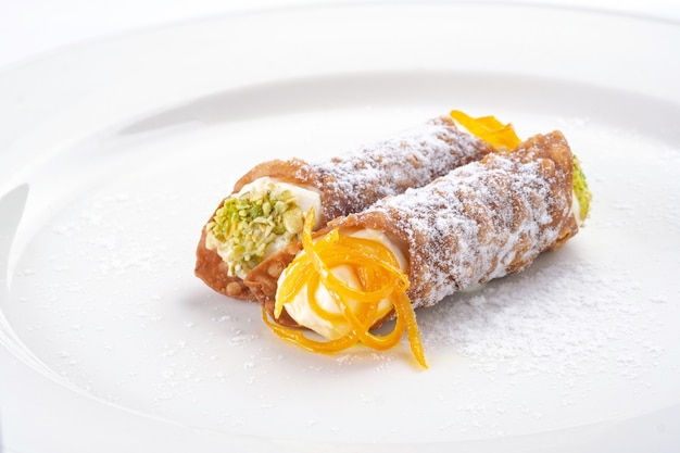 Cannoli doce sobremesa siciliana com queijo ricota e pistache em prato branco