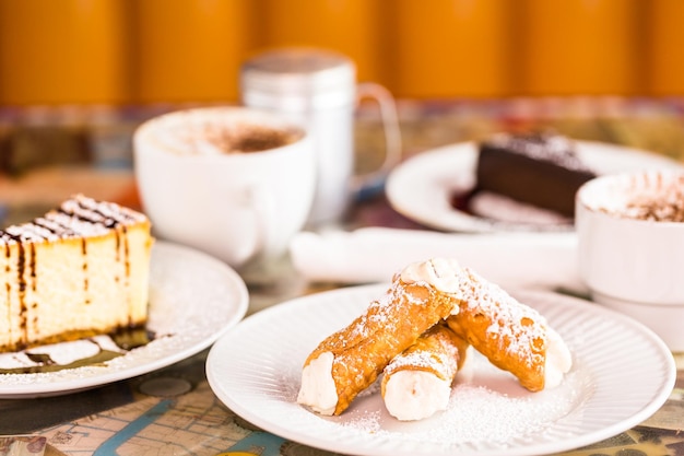 Cannoli italiano fresco con café en la mesa.