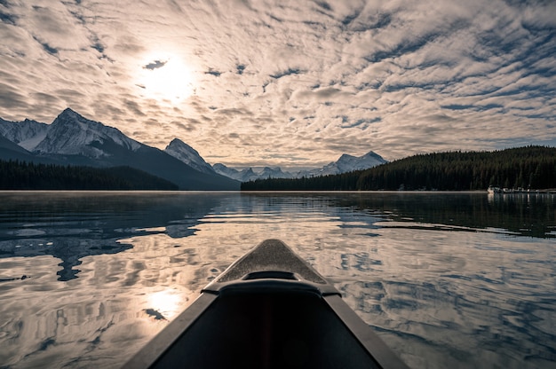 Canoagem com Montanhas Rochosas canadenses e luz do sol nublado no lago Maligne no Parque Nacional Jasper