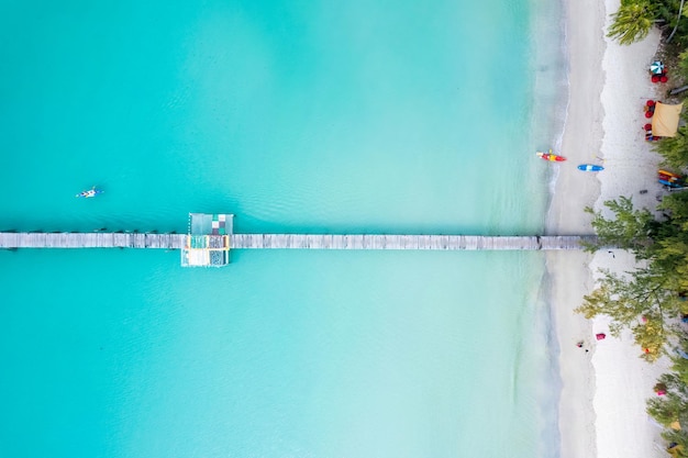 Canoagem turística pelo cais de madeira no mar turquesa e a praia no verão na ilha tropical