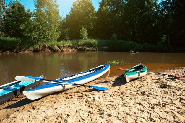 Las canoas turísticas con remos se paran en la costa del río en verano en una caminata acuática Rafting en botes de kayak inflables y de estructura doble y triple viaje familiar aventura extrema en verano