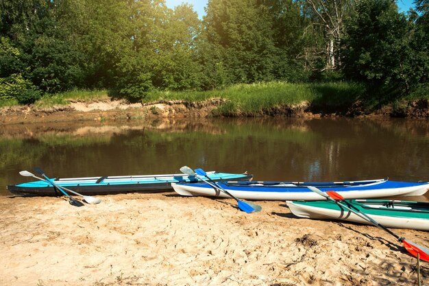 Las canoas turísticas con remos se paran en la costa del río en verano en una caminata acuática Rafting en botes de kayak inflables y de estructura doble y triple viaje familiar aventura extrema en verano