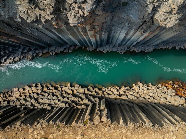 Cañón de columnas de basalto acantilado con río turquesa en Islandia foto aérea