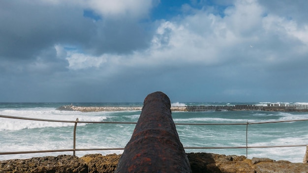 Foto canon negro antiguo apuntando hacia el océano en ericeira portugal