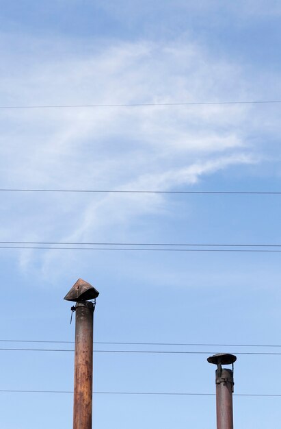 Canos de chaminé de metal antigos em um fundo de céu azul e fios