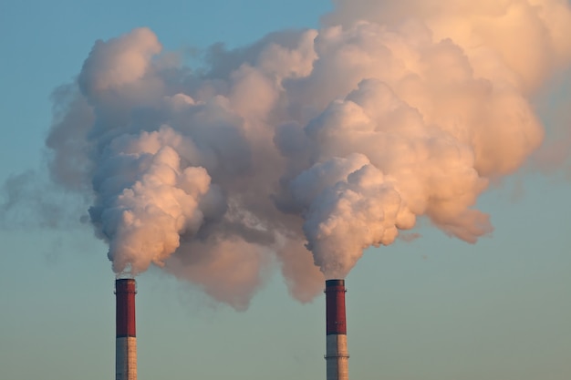 Canos de fábricas lançando nuvens de fumaça e poluindo o ar