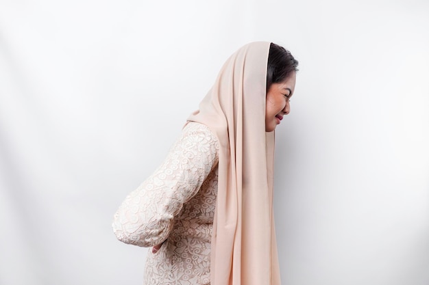 Cansada y molesta, una joven musulmana asiática usa un pañuelo en la cabeza que sufre de dolor espasmo muscular en el lugar de trabajo Fatiga, fecha límite, dolor y postura incorrecta