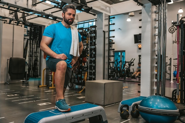 Cansado após o treino. Homem com toalha no ginásio após o treino