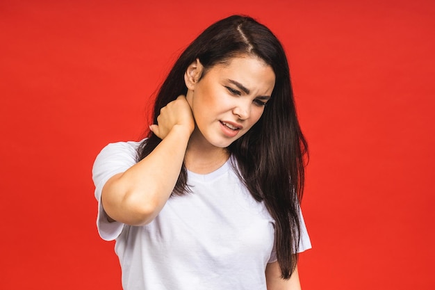 Cansado e infeliz jovem bela mulher com dor no pescoço isolada sobre fundo vermelho