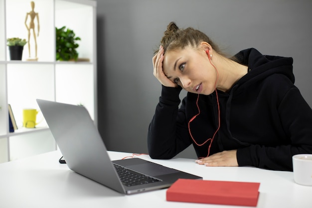 Cansado freelancer confuso, trabalhando no laptop, segura a mão na testa, burnout