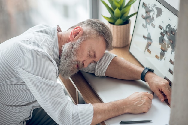 Cansado. Un hombre durmiendo en el lugar de trabajo sintiéndose cansado.