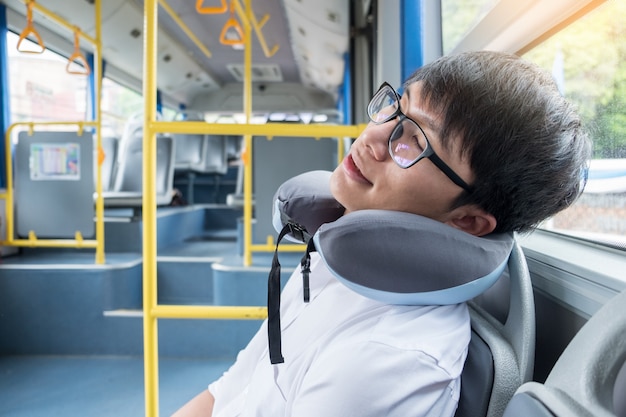 Cansado homem confortavelmente em ônibus e dormir com travesseiro inflável cervical pescoço, transporte